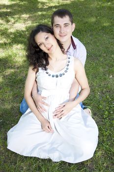 Man and a pregnant woman hugging in summer park