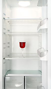 Red wine in a glass in an empty refrigerator
