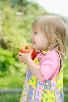 The little girl holds an apple in hands