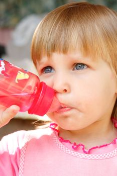 The girl drinks water from a bottle