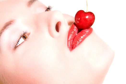 Beautiful woman with bright red lips giving a kiss to a cherry