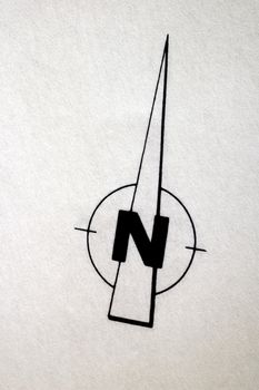A compass rose, indicating North, on textured draughtsman's paper of a building plan. The paper is slightly grungy from use. Space for text in the image.