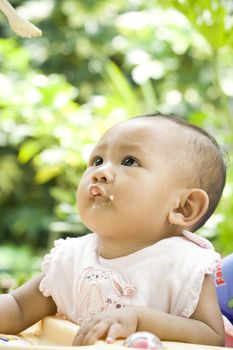 7 months asian baby girl looking up to a spoon of meal. ready to eat