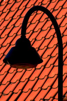 Street lamp next to a red tiled roof