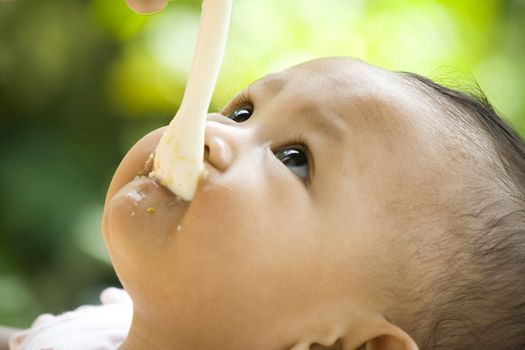 7 months baby looking up while having a meal with spoon in mouth