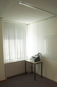 Fax machine standing in an office next to a window