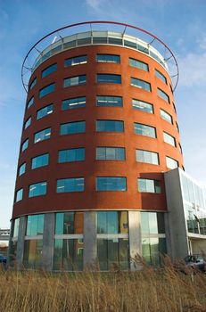 Modern round-shaped office building made of red brick and glass in Hoogvliet, Holland