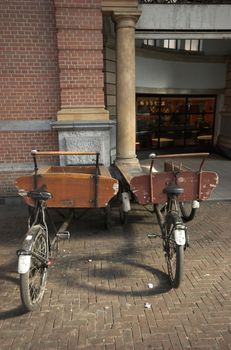 Two antique bicycle trailers for transporting food, parked und the roof of a railway station in Holland