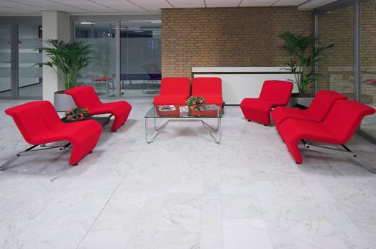 Set of red chairs arranched around a table, office waiting area