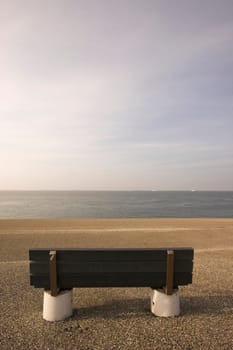 Wooden bench standing at the concrete covered seaside edge in Den Helder in Holland