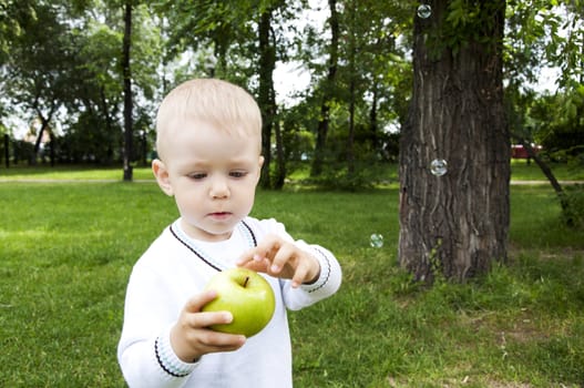 Portrait of a preteen boy with a apple in his hand and green grass in the background