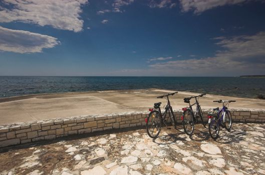 Three bicycles parked at the edge of a sea
