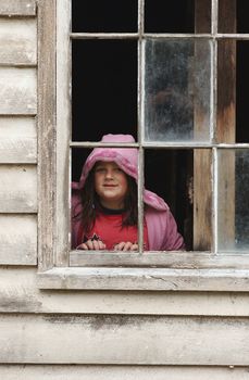 A girl looks out an old shed window