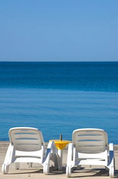 Two plastic chairs at the edge of a sea