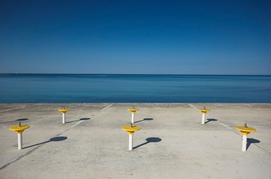 Umbrella holders on a terrace next to a sea