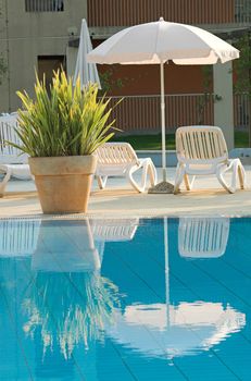 Plastic white chairs standing on a swimming pool terrace