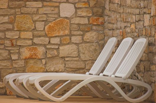 White plastic seats standing on a terrace next to a pool