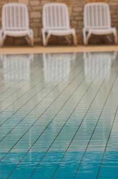 White plastic seats standing on a terrace next to a pool