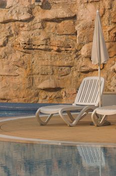 White plastic seats standing on a terrace next to a pool