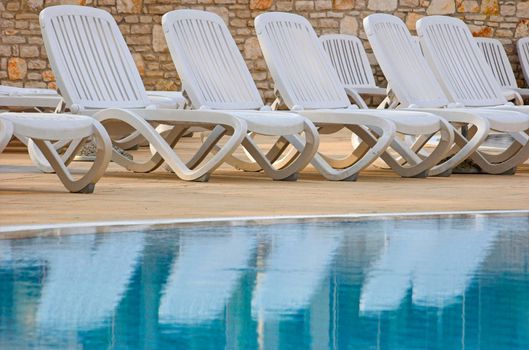 Plastic white chairs standing on a swimming pool terrace