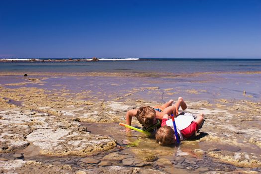 Two boys explore the shallow rock pools close up. Te Angiangi Marine Reserve in Central Hawkes Bay, New Zealand