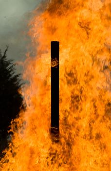 A stake stands in the middle of a bonfire.