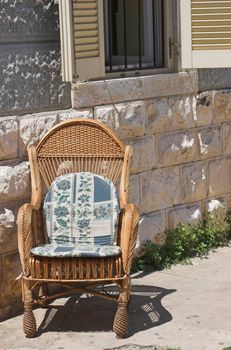 Rattan armchair standin in full sun on a terrace