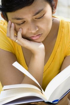 asian young woman feel sad while reading a book outdoor