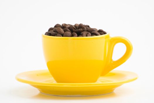 Yellow espresso cup filled with coffee beans