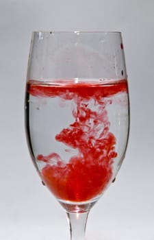 a cup of water with drops of red liquid