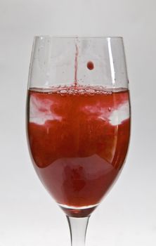 a cup of water with drops of red liquid