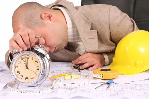 A businessman sleepy with architectural plans at desk