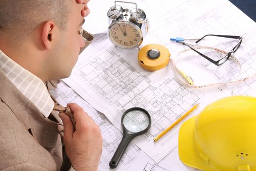 A businessman sleepy with architectural plans at desk