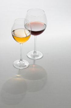 Two tall glasses on light background filled with red and white wine