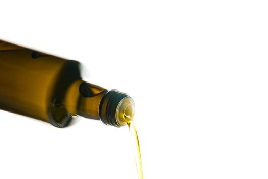 Olive oil being poured from a bottle isolated on white