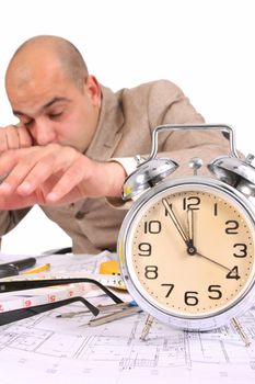 A businessman sleepy with architectural plans at desk