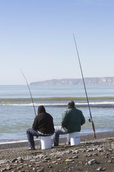 A couple of blokes fishing on a spring morning. Haumoana, Hawke's Bay, New Zealand. Cape Kidnappers in background.