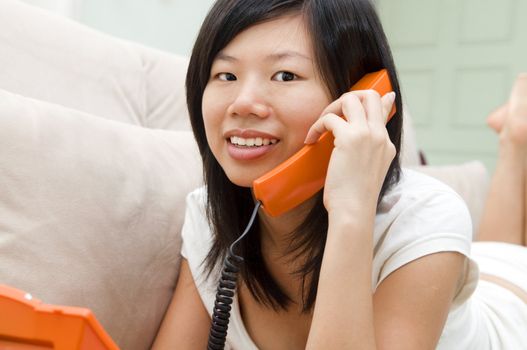 Asian woman on sofa chatting phone 