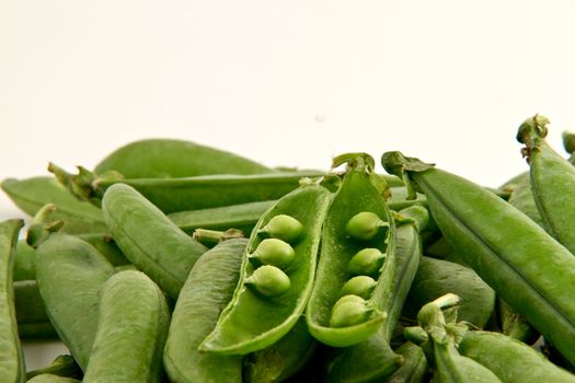 Bunch of green peas  with one open pod.