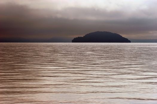 An island  in Lake Taupo shrouded by stormy weather. Taupo, New Zealand