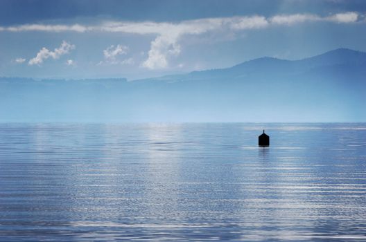 A buoy sits in Lake Taupo shrouded by stormy weather. Taupo, New Zealand