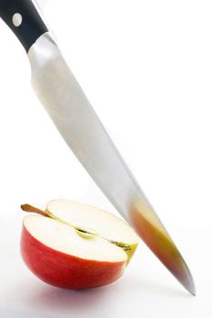 Long bladed kitchen knife cutting through a red apple