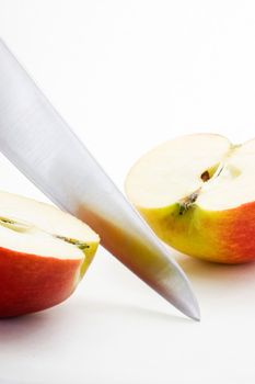 Long bladed kitchen knife cutting through a red apple
