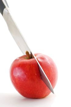 Long bladed kitchen knife cutting through a red apple