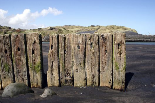 Wooden posts in black sand at Patea, Taranaki, New Zealand