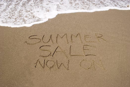 A summer sale written in the sand