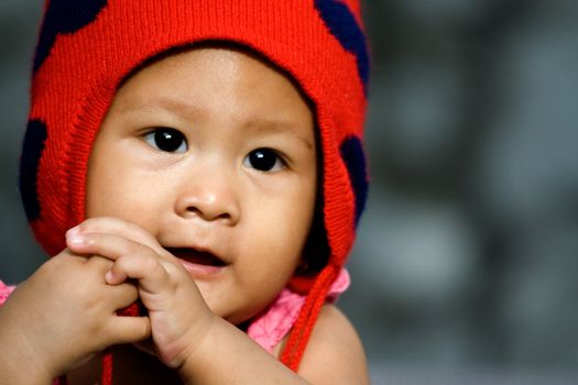 portrait of a cute asian baby girl with a red hat seems to have enjoyment