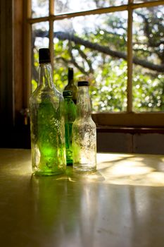 Old glass bottles sit on a formica table in a bach on Rangitoto Island