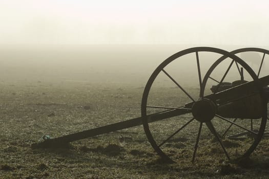 Old Farm Machinery stands in a bare field on a foggy morning. Haumoana, Hawke's Bay, New Zealand