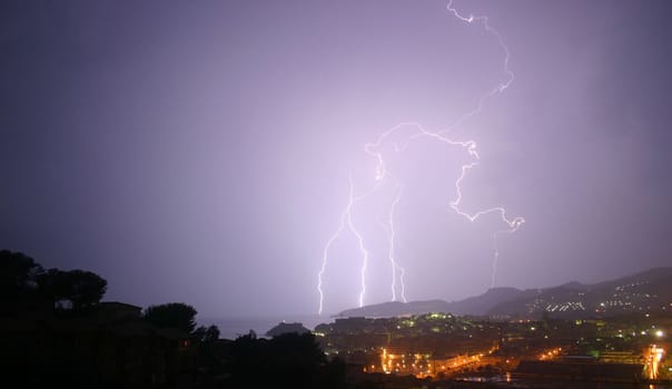 3 lightning photos shot from the same viewpoint.  Same landscape, choice of bolts.  The image is taken from a high viewpoint, overlooking trees, a town and mountains.